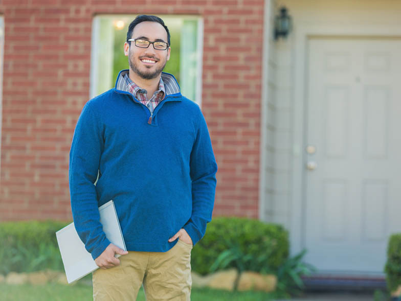 Man standing out front of house smiling