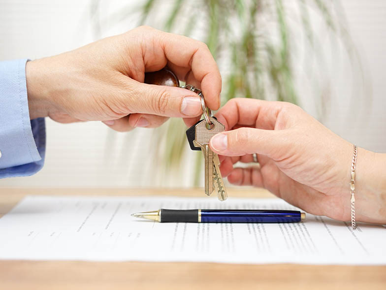 Person passing keys to other person above signed lease agreement