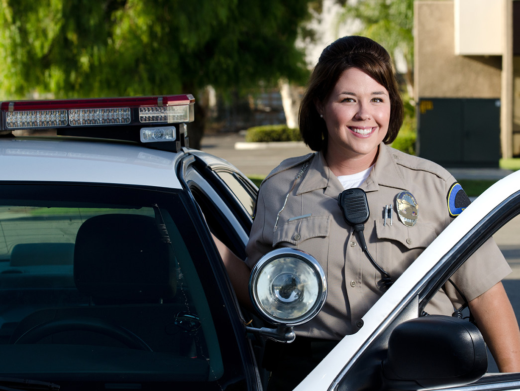 Police woman smiling next to her car