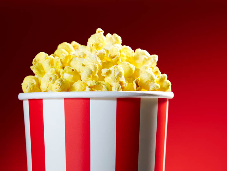 Bin of popcorn against red background