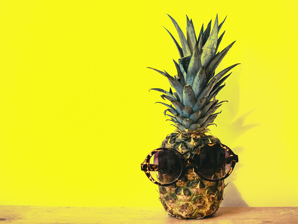Pineapple wearing sunglasses on yellow background