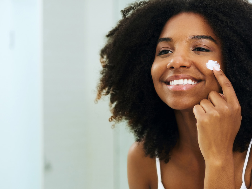 Woman smiling and putting cream on her face