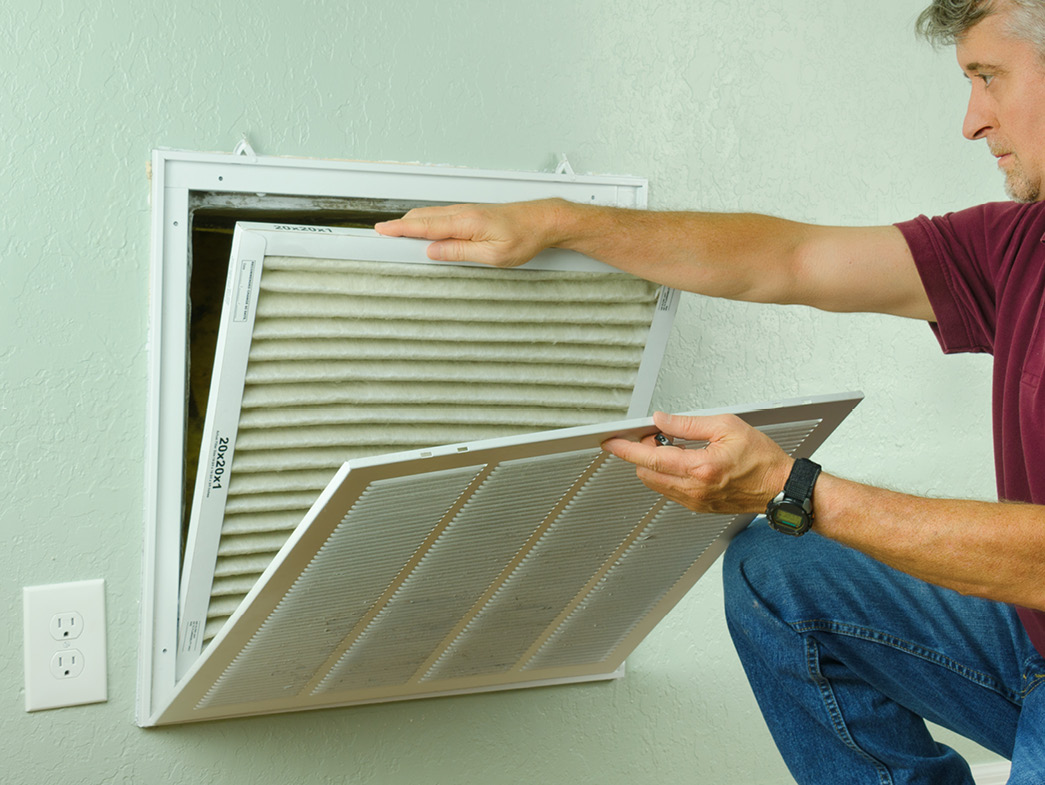 Man replacing filter in air vent
