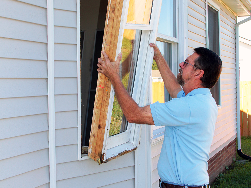 Man installing a window into side of home