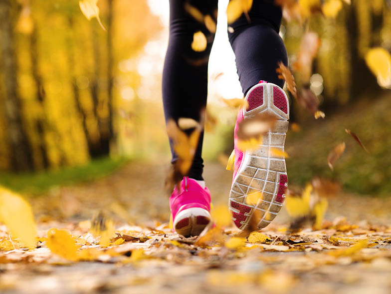 Woman jogging with yellow leaves falling