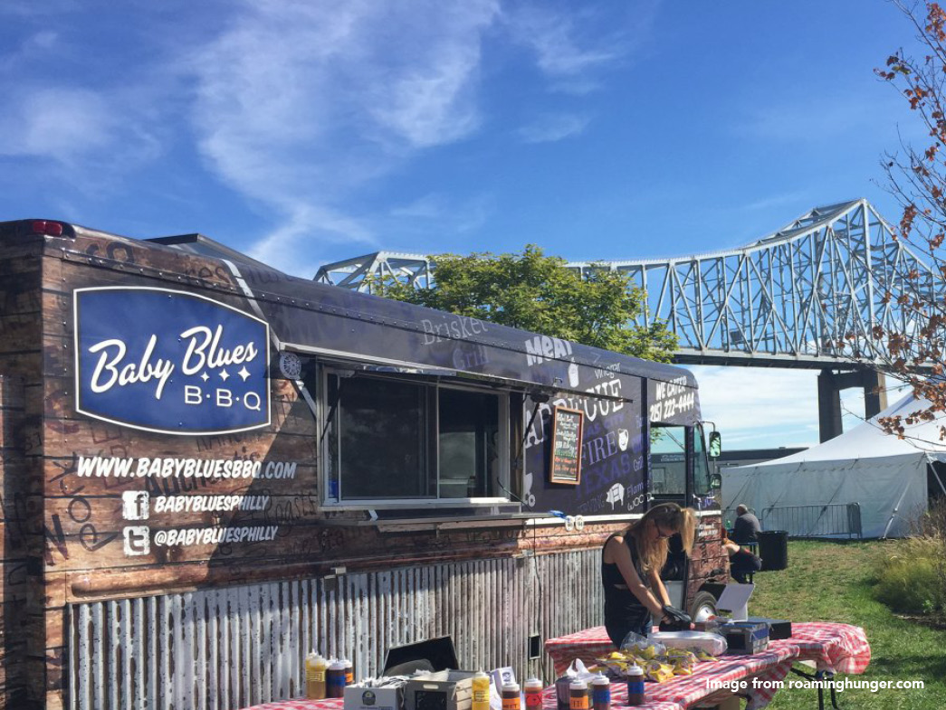 Food truck with river and bridge in background