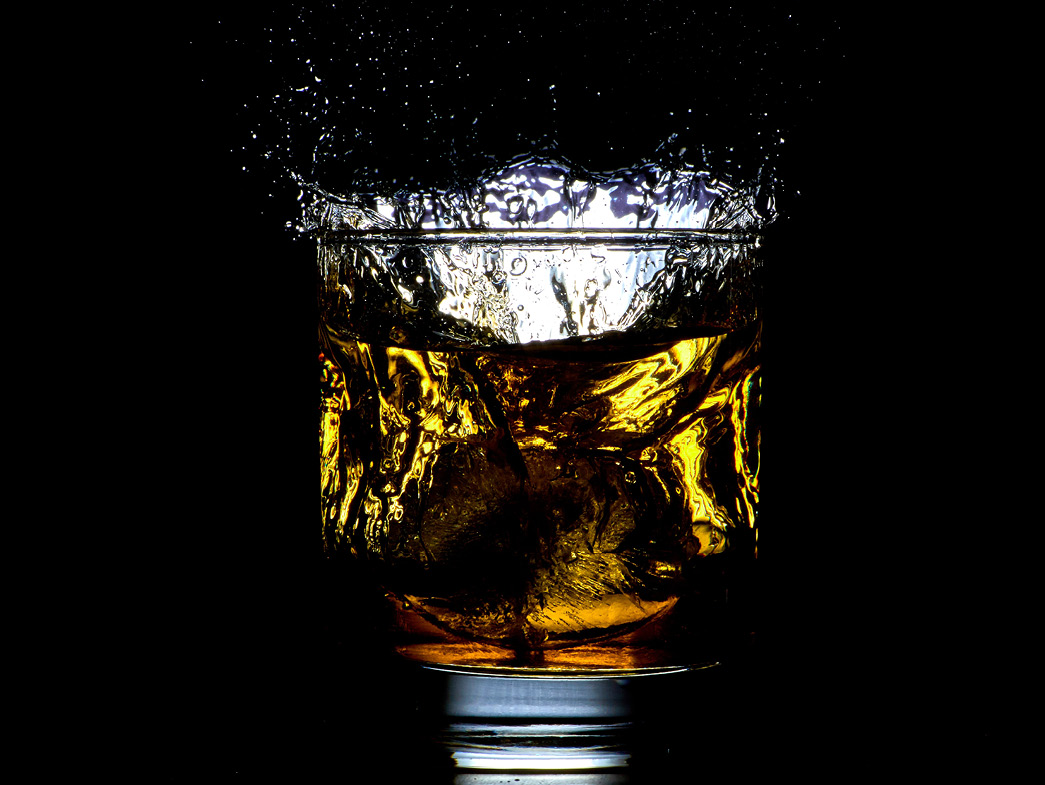 Bourbon in glass with ice on black background