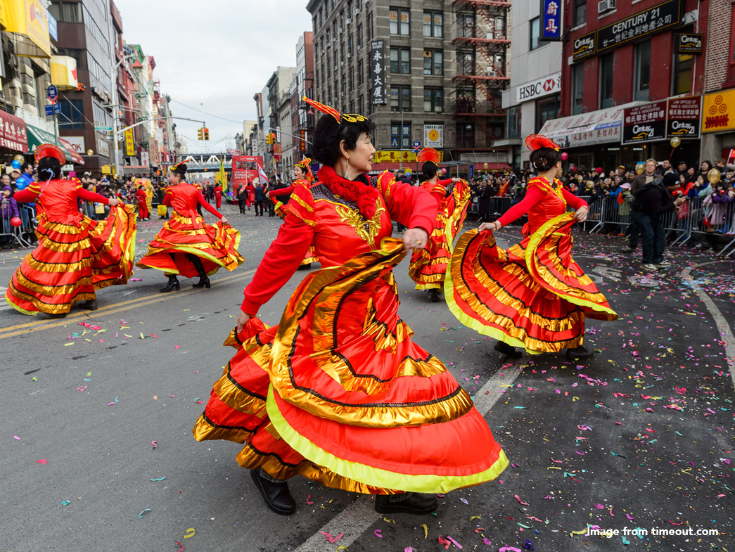 Chinese women dressed in red and gold dresses dancing in the street
