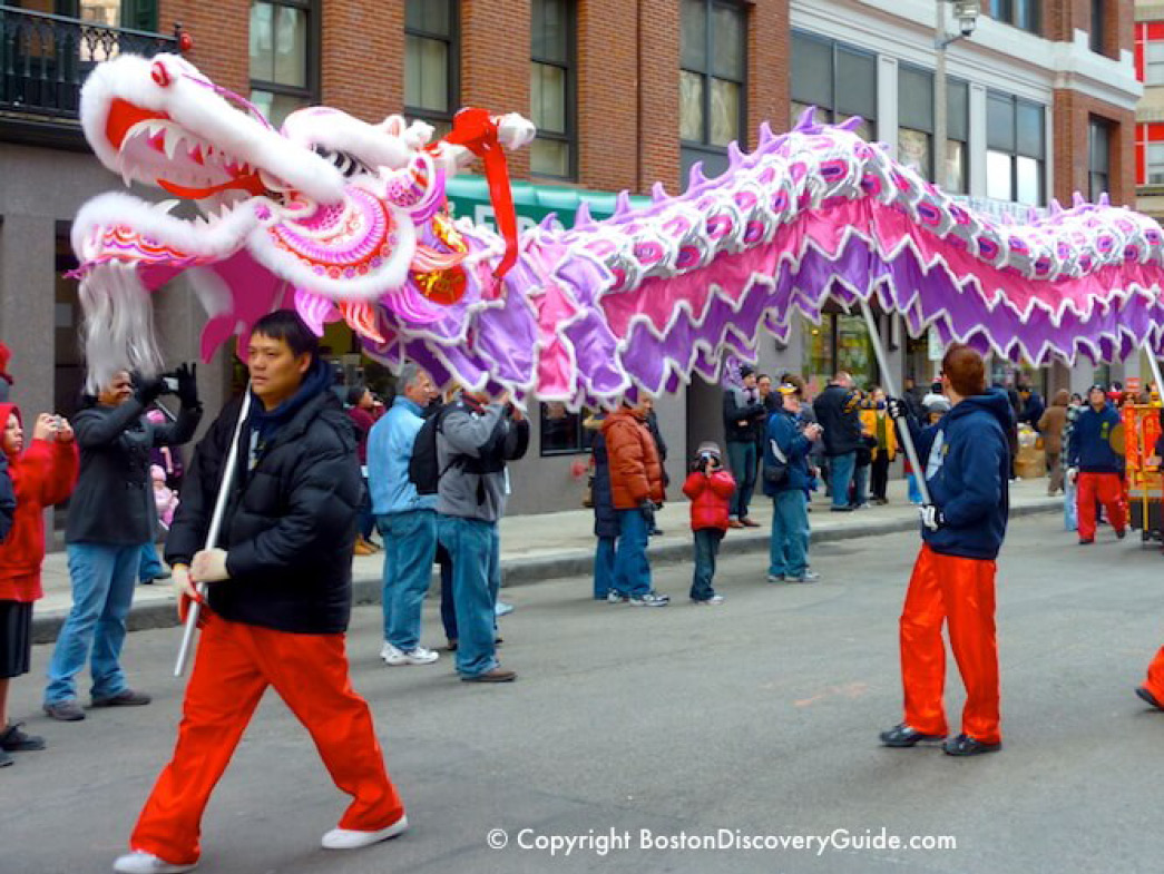People carrying dragon sculpture down street in parade