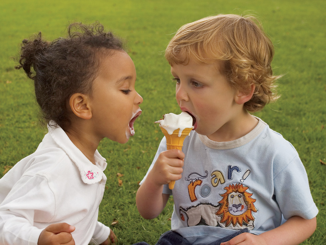 Kids in grass sharing ice cream cone