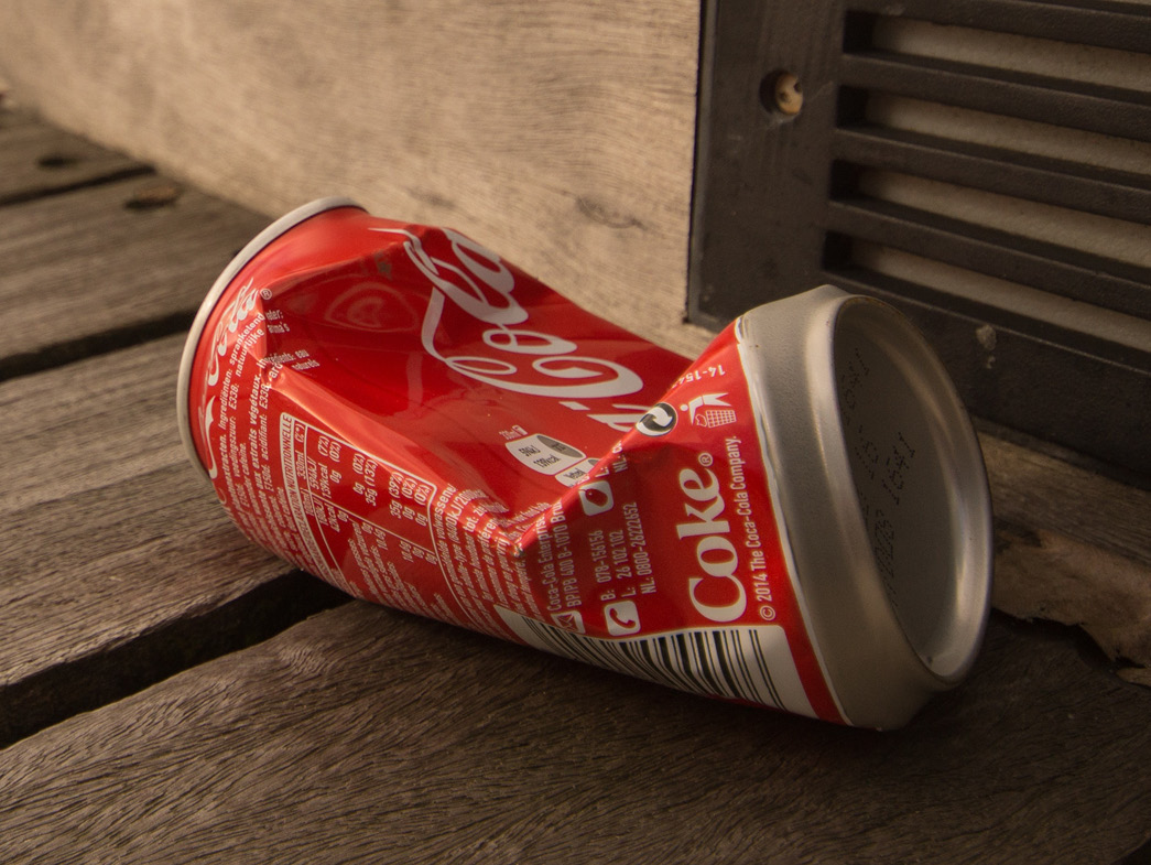 Aluminum coca-cola can laying crumpled on ground