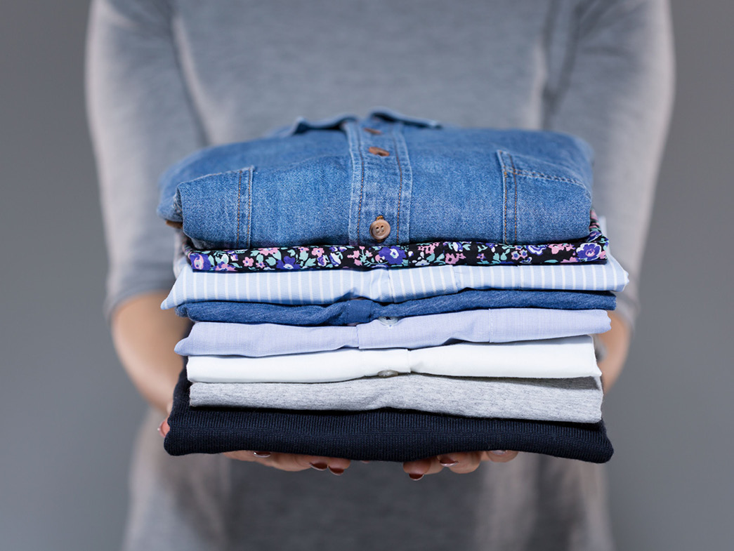Woman holding stack of neatly folded clothes