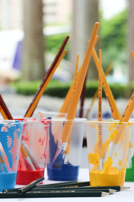 cups of paint with paintbrushes