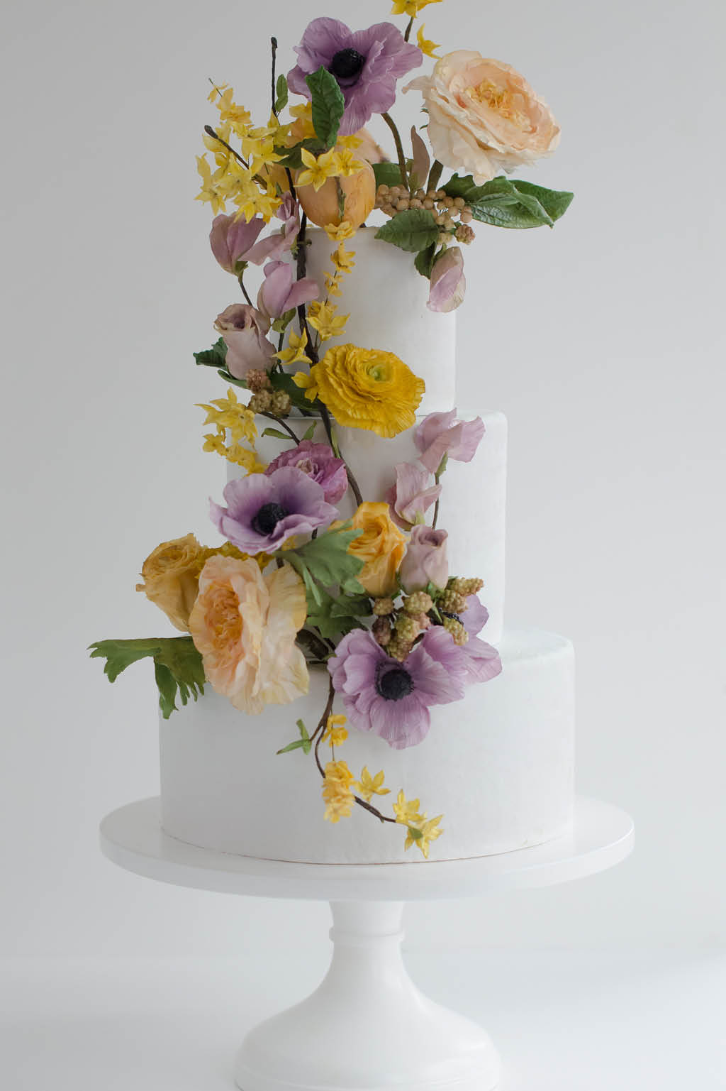 white tiered cake with purple and yellow flowers