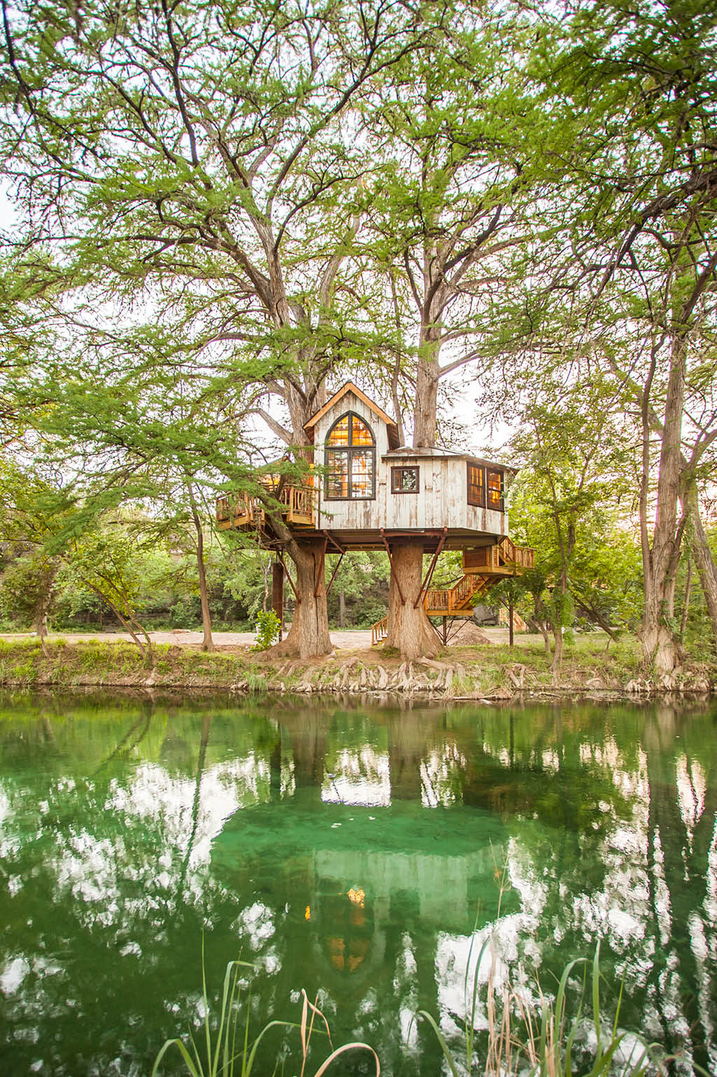 white treehouse above water surrounded by trees