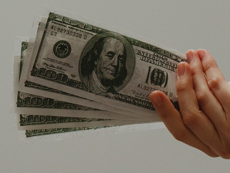 hand holding hundred dollar bills
