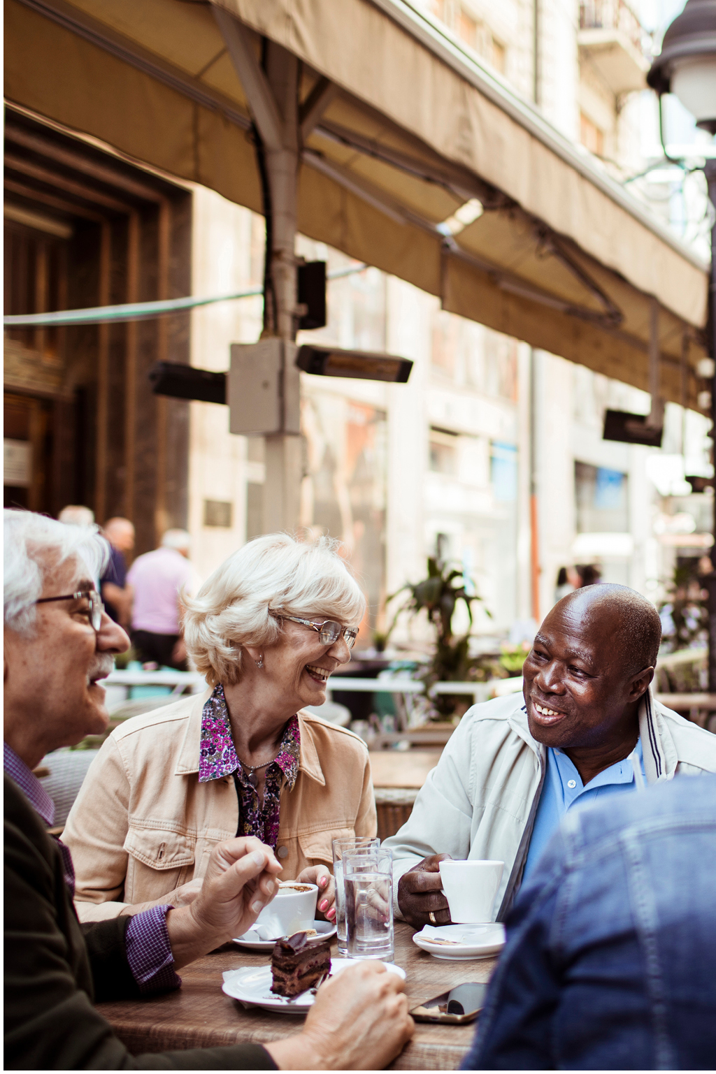 older woman and two older gentleman sharing coffee