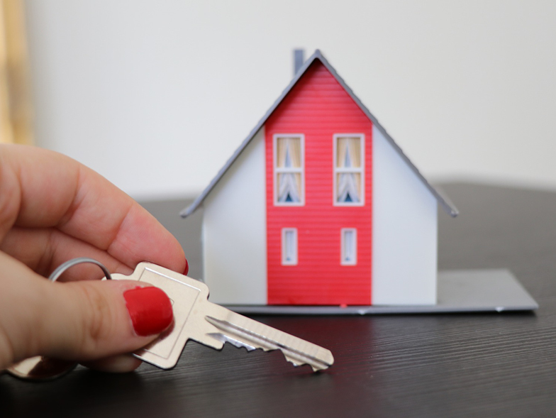 miniature house with hand holding a key