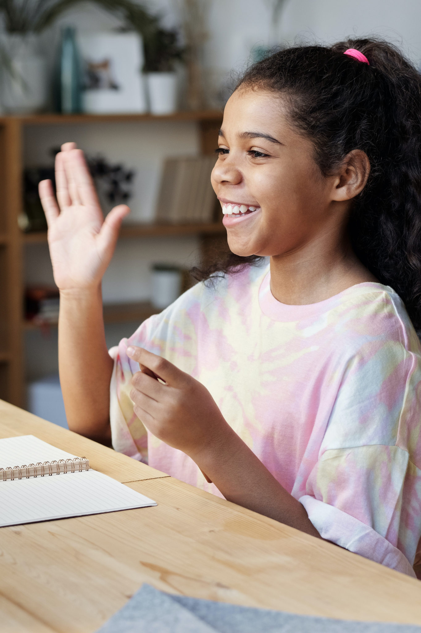 young girl waving at computer