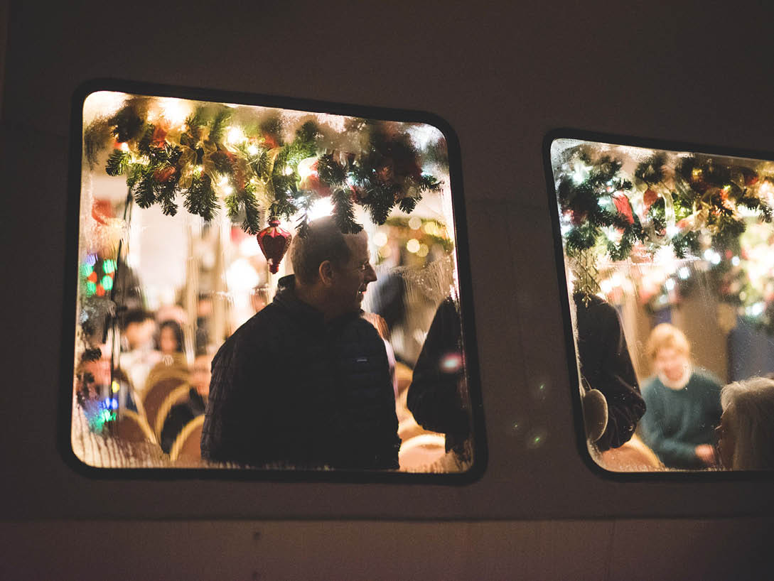 man sitting at window with christmas lights