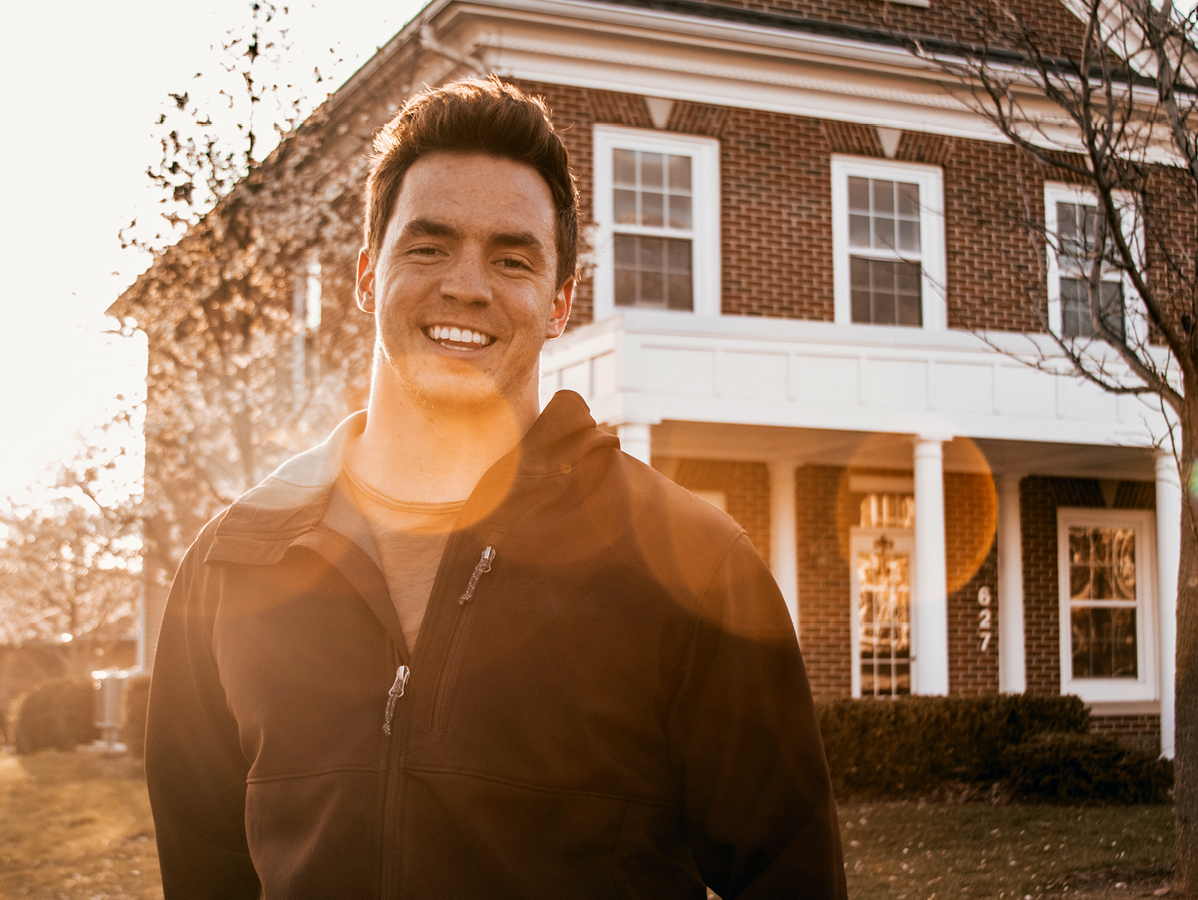 young man standing on front of a home at sunset