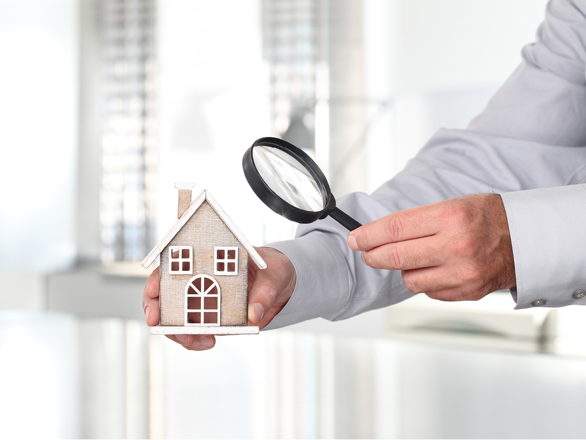 person holding a magnifying glass up to a model home