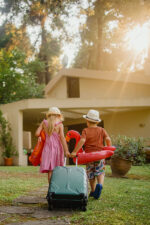 Two children returning home from vacation with luggage