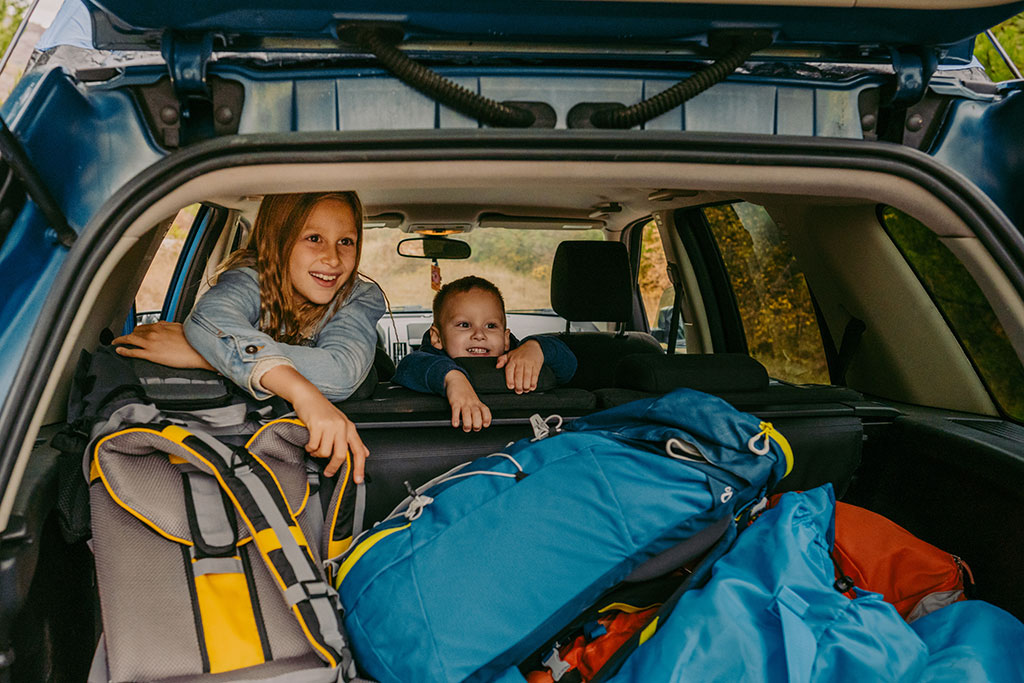 Kids in car excited with trunk full of luggage