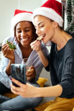 Two women taking selfie eating christmas cookie