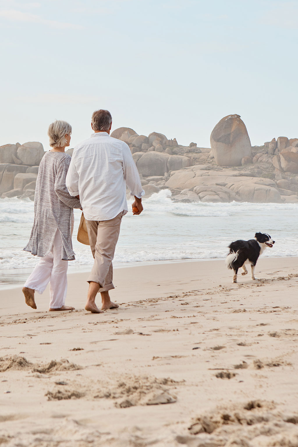 Older couple and dog walking on beach