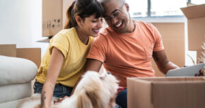 Couple packing moving boxes with dog