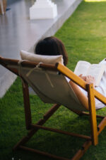 Woman sitting in lounge chair reading book