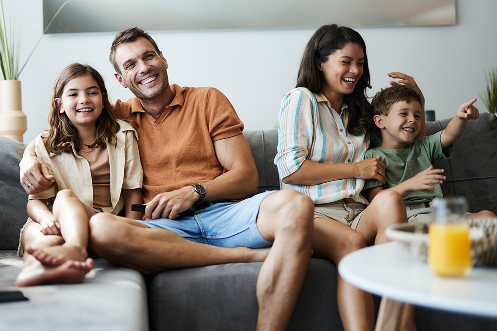 Family sitting on couch laughing watching movie